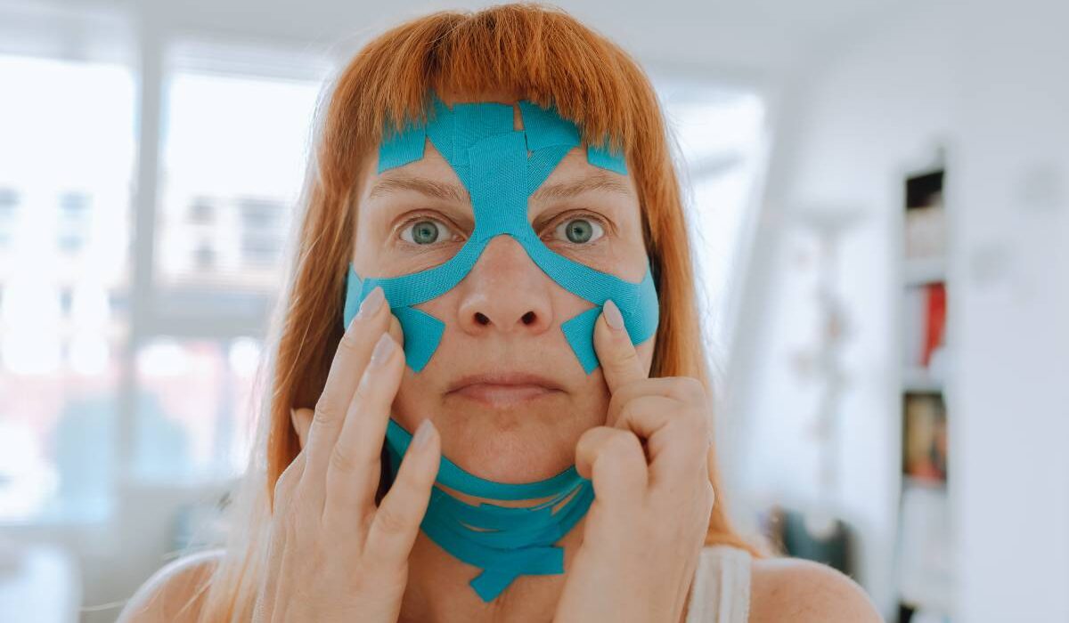 Close-up portrait middle-aged woman, she puts kinesiology tape on face