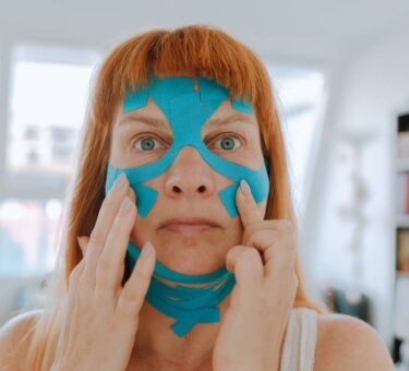 Close-up portrait middle-aged woman, she puts kinesiology tape on face