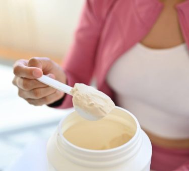 Young woman in sportswear hand holding scoop making protein shake after morning workout. Healthy lifestyle concept